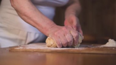 Dişilerin elleri ahşap masada hamuru yoğuruyor. Ekmek ürünleri ve arka plan. Kadın mutfakta hamur hazırlıyor, ağır çekimde..