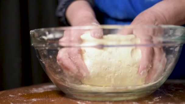 Avó cozinhar, preparando a massa de farinha, as mãos da avó fecham-se. Mulher sênior assar pastelaria em sua cozinha em casa. Movimento lento — Vídeo de Stock