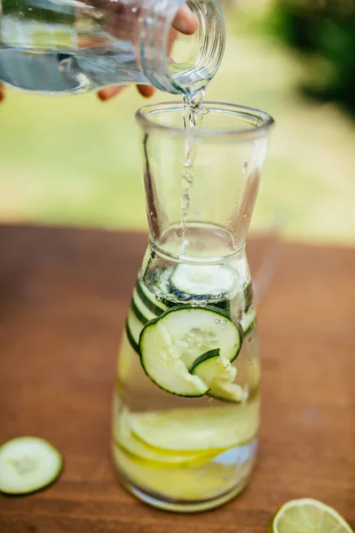 Verser de l'eau dans la bouteille avec du concombre — Photo