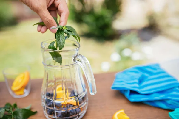 Colocación de menta en la botella de vidrio con arándanos y naranja —  Fotos de Stock