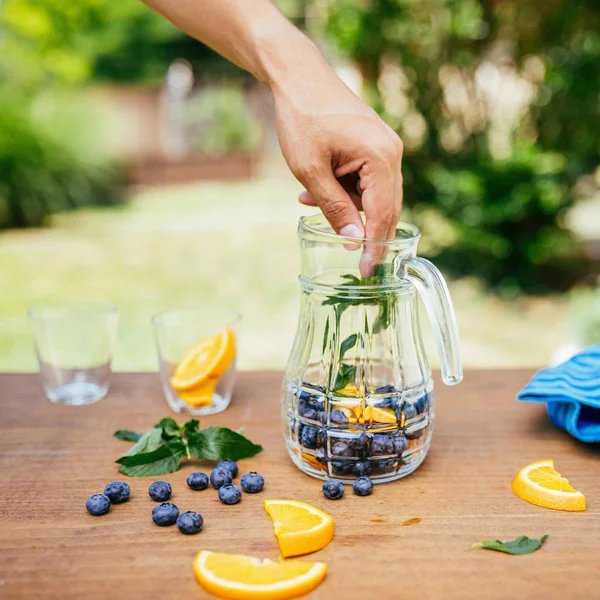 Colocación de menta en la botella de vidrio con arándanos y naranja —  Fotos de Stock