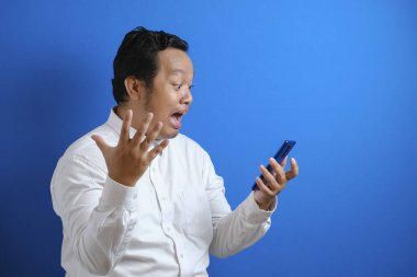 Ofis çalışanı Asyalı bir adamın akıllı telefonundan aldığı habere üzülen bir fotoğrafı. Adam hayal kırıklığına uğramış bir jest yaptı.