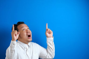 Asyalı bir ofis çalışanı parlak bir fikir bulduğu için mutlu görünüyor. Zafer ifadesi gösteren ve parmağını kaldıran bir adam.