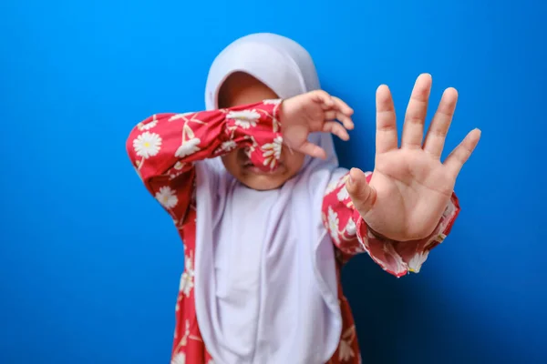 Little muslim girl suffering bullying raises her palm asking to stop the violence