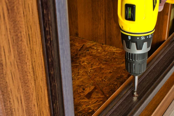 Twisting self-cutters with a screwdriver. cabinet repair with a drill — ストック写真