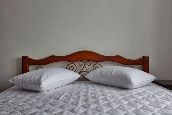Λευκά σεντόνια και μαξιλάρια στο κρεβάτι μαόνι — Φωτογραφία Αρχείου