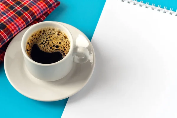 Bloc-notes avec espace de travail blanc pour les inscriptions à côté d'une tasse de café et une serviette rouge sur un fond bleu — Photo