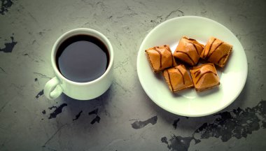 Bir fincan sade kahve ve gri beton arka planda çikolata jöleli bir tabak. Tatlı lezzetli.