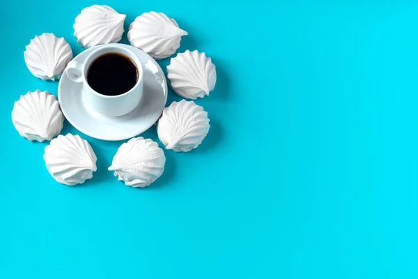 Guimauves blanches à la vanille disposées en cercle sur un fond bleu et au milieu une tasse de café — Photo