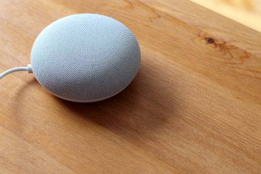 Bir Google Yuva Mini akıllı konuşmacı ahşap bir masada oturur