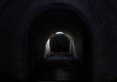 Fort Pospelova 'daki kasvetli, karanlık bir yeraltı geçidi, tavandaki bir kapaktan güneş tarafından aydınlatılıyor..