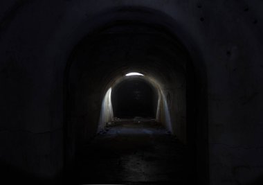 A gloomy dark underground passage at Fort Pospelova, lit by the sun through a hatch in the ceiling. clipart
