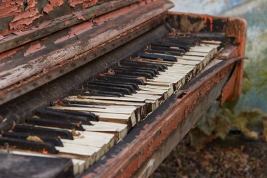 An old broken piano in the street with a large pan with white and black keys.
