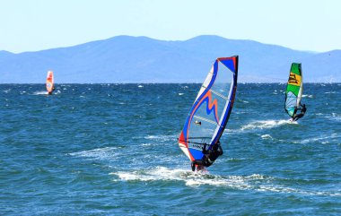 Vladivostok, Russia - October, 05, 2019: Surfers on a sunny autumn windy day in the waters of the Amur Bay in Vladivostok.