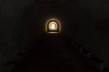 A lighted door leading to freedom from a gloomy dark underground passage at Pospelov Fort in Vladivostok. clipart