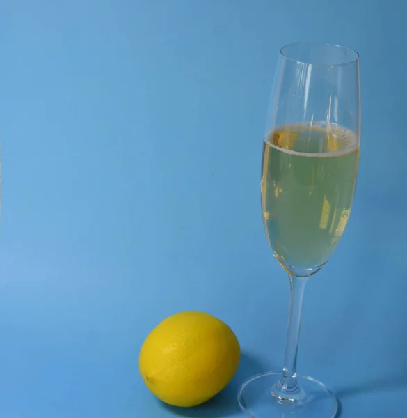 ブルーの背景にシャンパンスタンドを持つ眼鏡 黄色のレモンがあります — ストック写真