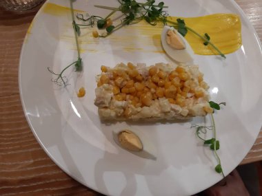 Beyaz tabakta Sicilya salatası var. İçindekiler: tavuk fileto, ananas, mısır, yumurta, hardal sosu, bezelye filizleri.