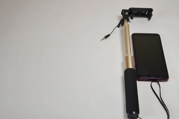 一个博主的一套 在白色背景的智能手机和用于摄影和视频的自拍棒上 — 图库照片