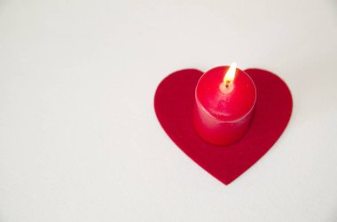 Sevgililer Günü. Beyaz arka planda kırmızı bir mum ve keçeli bir kalp var..