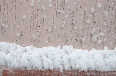 Geçmişi ve dokuları. Duvarda, pembe sıva kaplı, beyaz tüylü kar yapışmış.