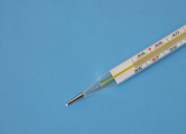 İlaçlar. Mavi arka planda sağlık hizmeti bir insanın vücut ısısını ölçmek için bir cam termometre.