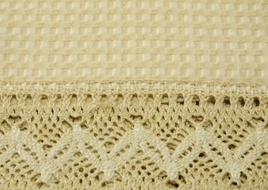 Dokular ve arka planlar. Renkli kurdelelerle işlenmiş bej rengi dantellerin ve çiçeklerin masa örtüsünün üzerinde..