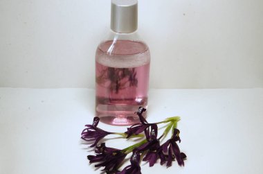 Hafif bir arka planda mikiler suyu ve mor süsen çiçekleriyle dolu bir şişe..