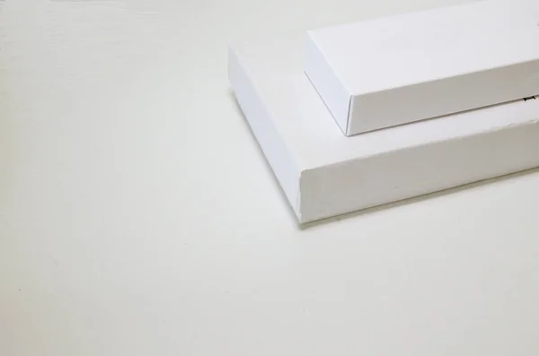 On a white background two white packaging boxes of different sizes.