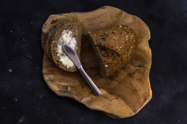 Tahtaya bıçak saplanmış bir somun ekmek. Karanlık arka plan. Üst görünüm.