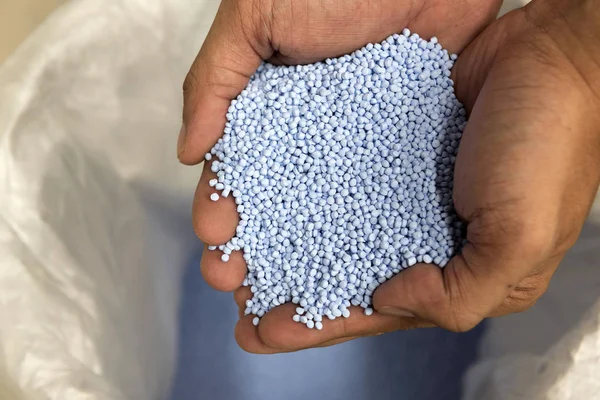 Kezében kék színű nyers műanyag gyöngyöket — Stock Fotó