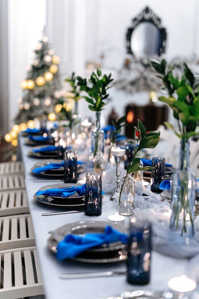 Long table setting decorated with fresh green leaves, plates, glasses and cutlery. Concept of fine dining, catering and exclusive private hire of an event space