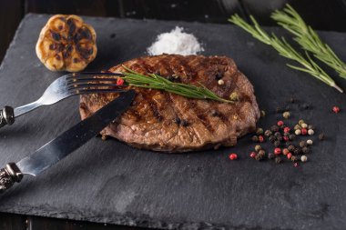 Çatal ve bıçak ile ahşap masa üzerinde taş plaka üzerinde sığır eti biftek ızgara.