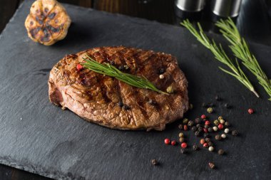 Çatal ve bıçak ile ahşap masa üzerinde taş plaka üzerinde sığır eti biftek ızgara.