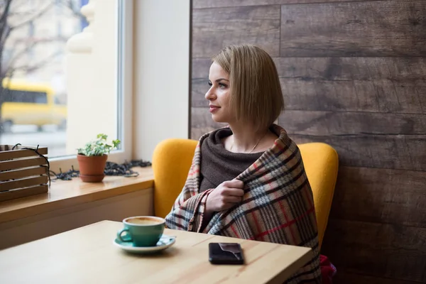 Woman drinking coffee in the morning at cafe. Soft focus on the eyes. Sellphone on table. — Stock Photo, Image