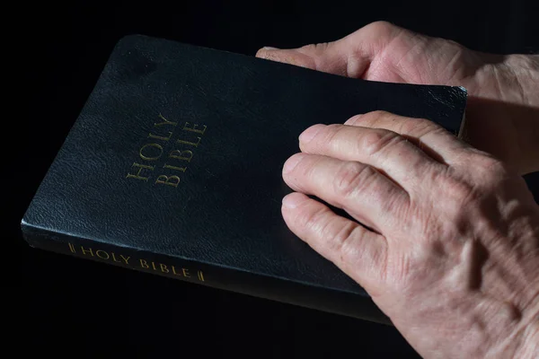 高齢者は、聖書が手をマンします。低ライト. — ストック写真