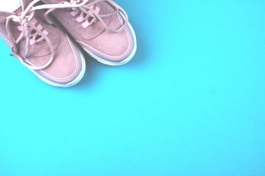 Mavi arka planda bir çift pembe spor ayakkabı.