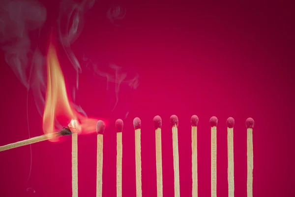 Burning matchsticks setting fire to its neighbors — Stock Photo, Image