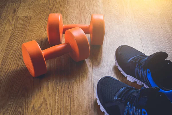 Zapatillas y pesas fitness sobre fondo de madera . —  Fotos de Stock