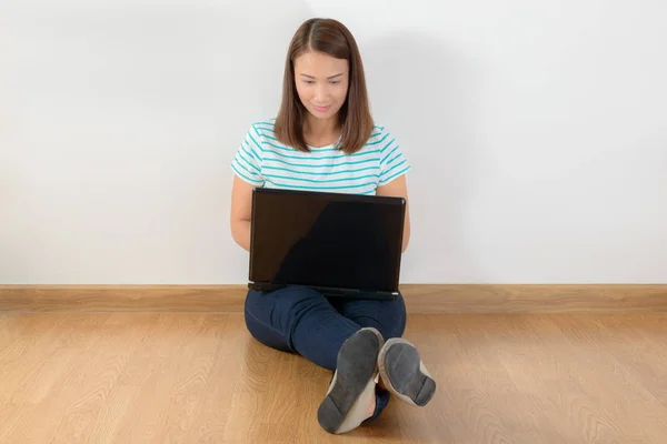 Joyeux jeune femme assise sur le sol avec les jambes croisées et usi — Photo