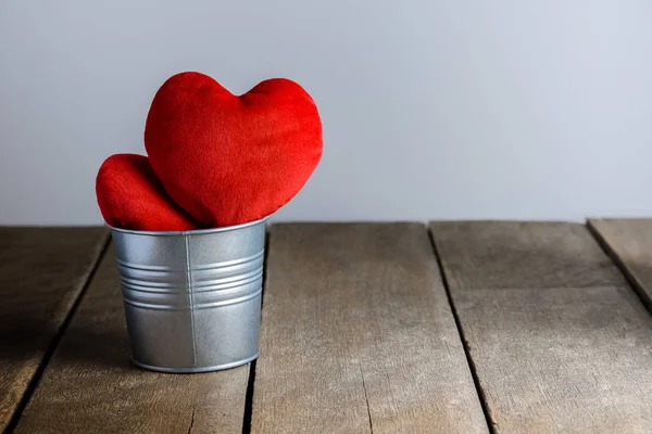 Červená srdce tvar polštáře v kovové lopaty na dřevěné pozadí — Stock fotografie