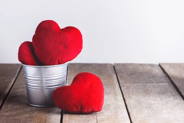 Červená srdce tvar polštáře v kovové lopaty na dřevěné pozadí — Stock fotografie
