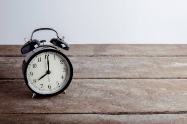 ahşap zemin ve gri arka plan üzerinde siyah çalar saat 
