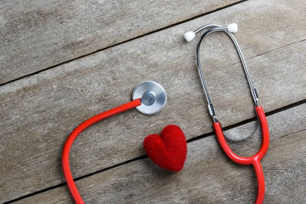 Hati merah dengan stetoskop pada latar belakang meja kayu — Stok Foto