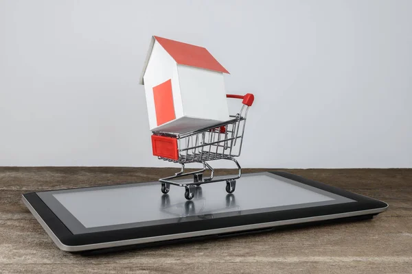 Huis model in winkelwagen op Tablet PC — Stockfoto