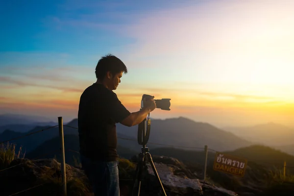 Fotografo silhouette sopra un mare nuvole, montagne nebbiose — Foto Stock