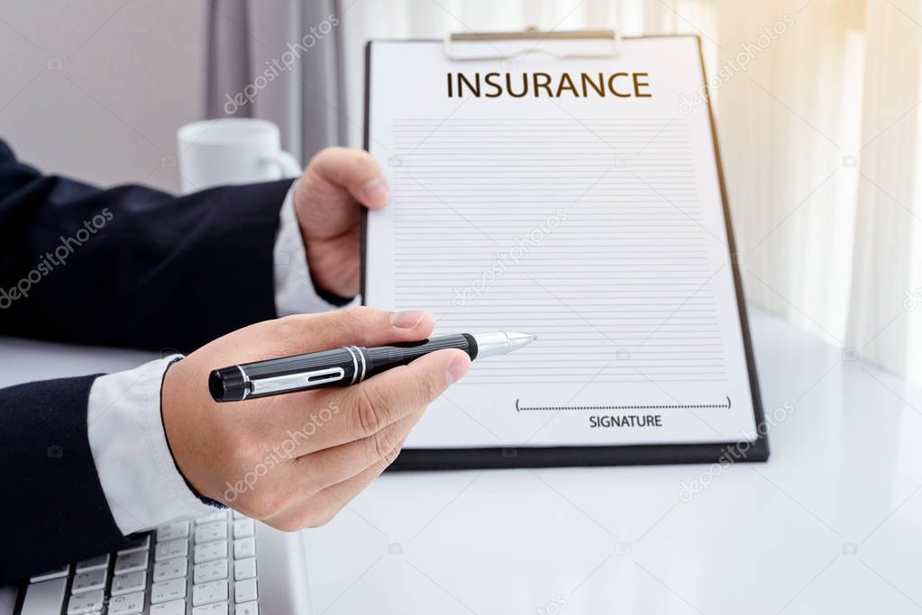 young man in suit in his office showing an insurance policy and 