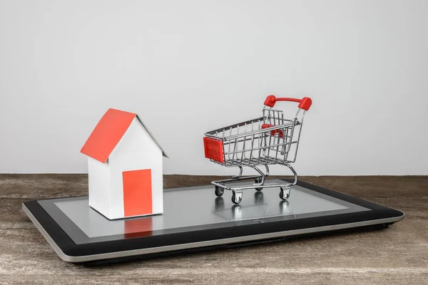 House model and shopping cart on tablet — Stock Photo, Image