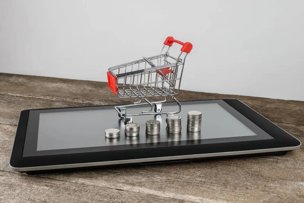 Alışveriş sepeti ve bozuk para yığınları Tablet — Stok fotoğraf