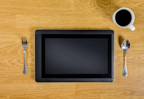 Tableta sobre mesa de madera con cuchara, tenedor y taza de café — Foto de Stock