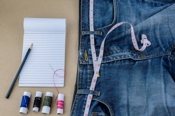 Jeans y cinta métrica, aguja, muchos hilos de color, bloc de notas, p — Foto de Stock